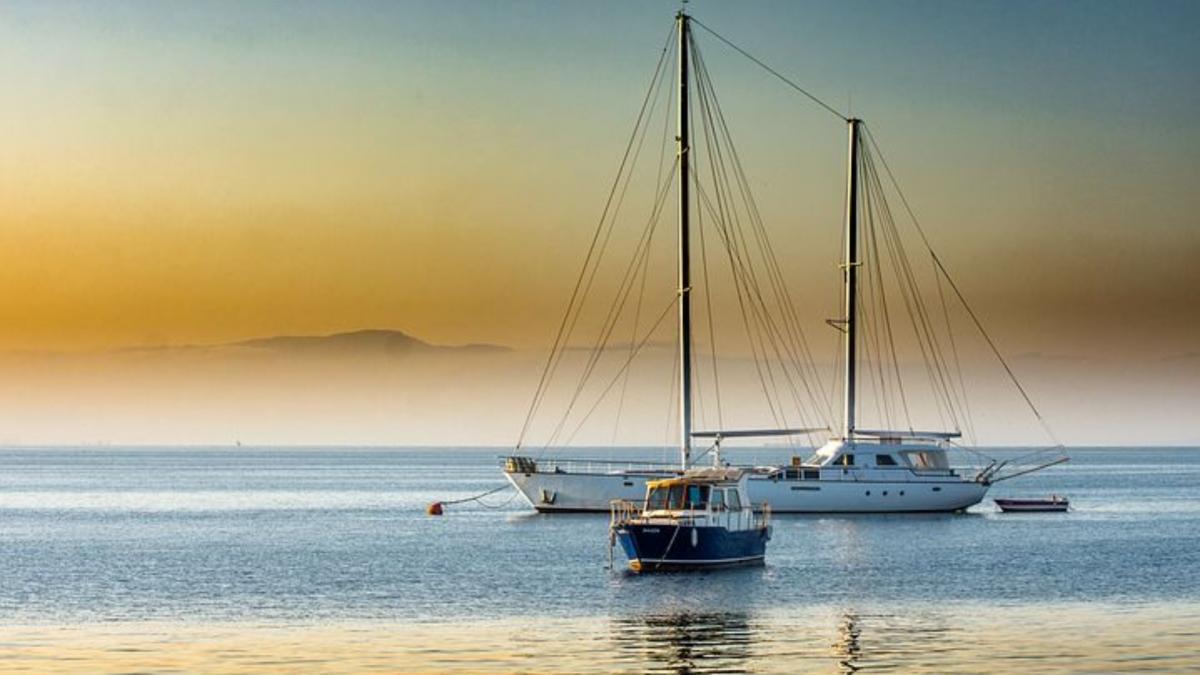 Two big boats and one small in the calm sea and a beautiful sunset 